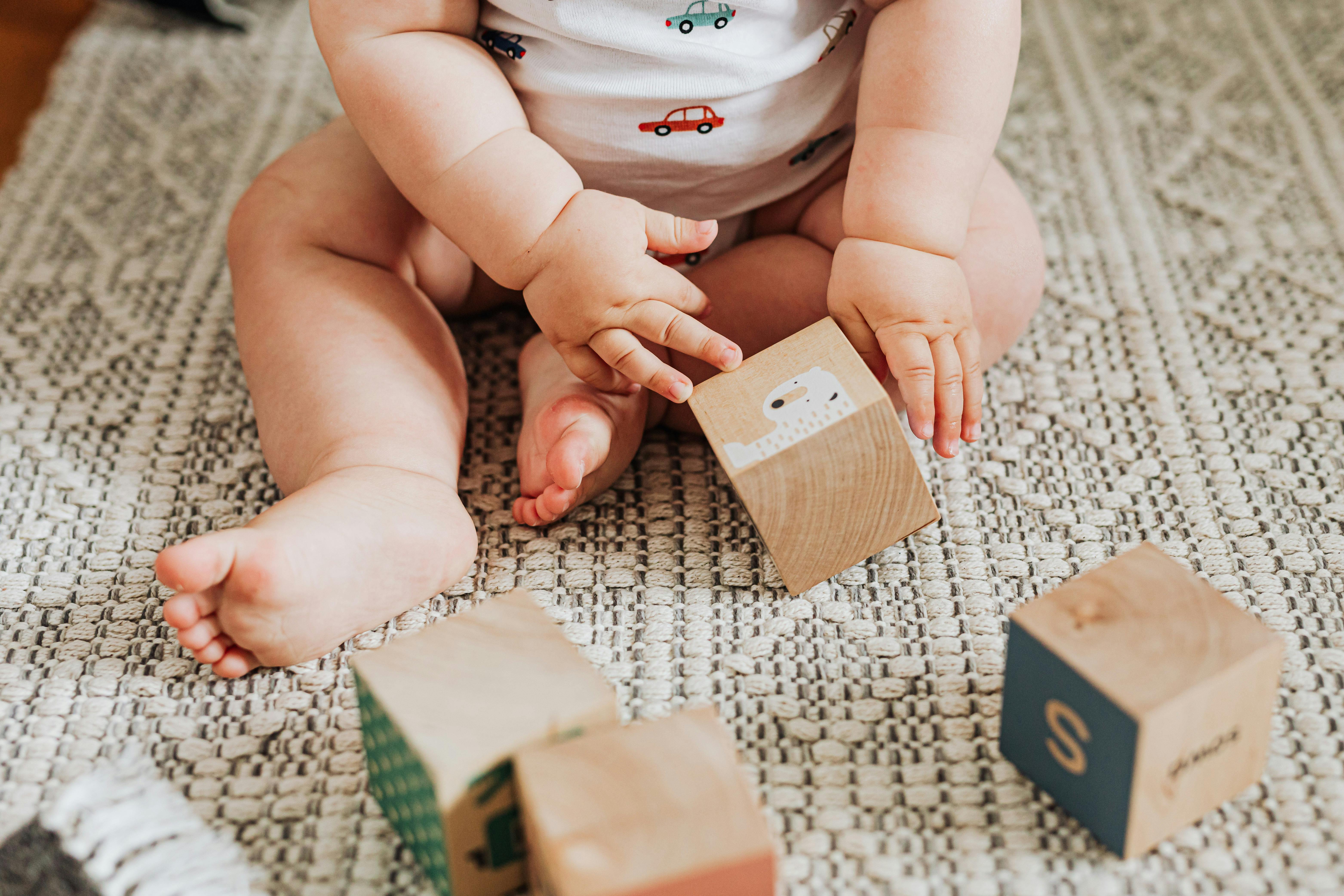 Un bébé jouant avec des cubes en bois sur un tapis