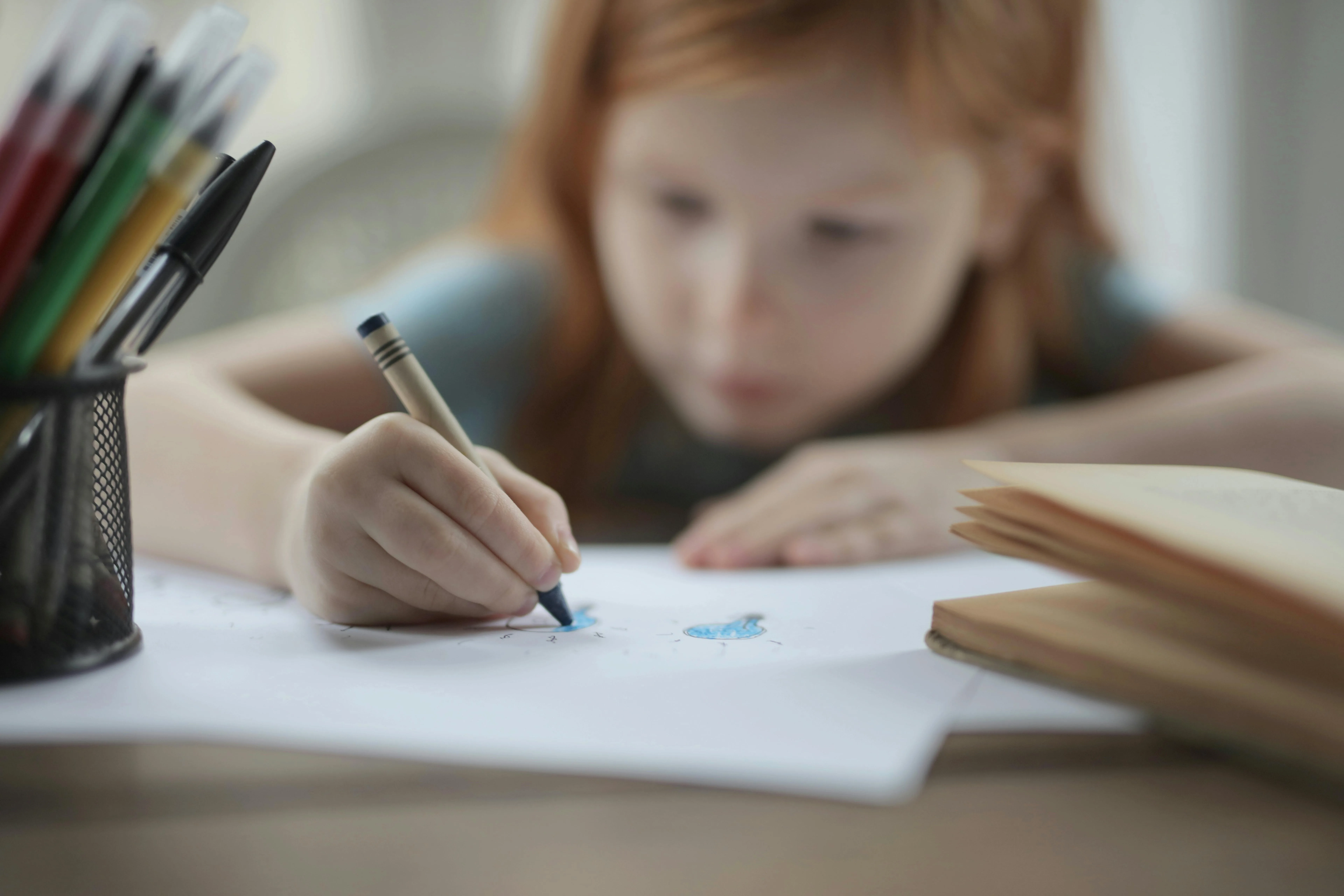 Enfant concentré qui dessine au crayon sur une feuille